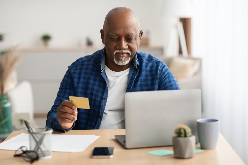 Senior Black Businessman Shopping Online Using Laptop Sitting In Office